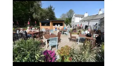 a group of people sitting at tables in a garden at Historic 1600’s The Grocer’s Cottage in Heysham