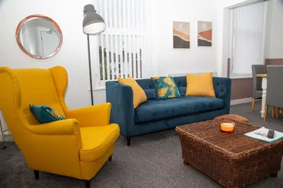 a living room with a blue couch and yellow chairs at Santiago 3 in Southport