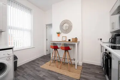 a kitchen with a counter and two stools in a room at Santiago 3 in Southport
