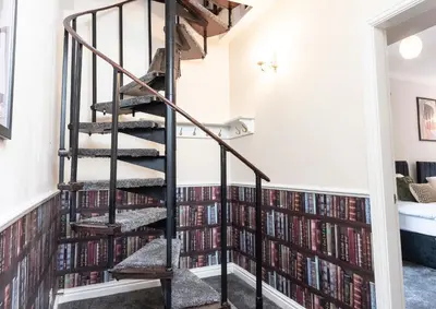 a spiral staircase in a room filled with books at St Andrews by Guestz in Lytham St Annes