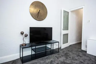 a living room with a television and a clock on the wall at St Andrews by Guestz in Lytham St Annes