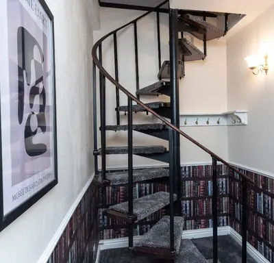 a spiral staircase in a room filled with books at St Andrews by Guestz in Lytham St Annes