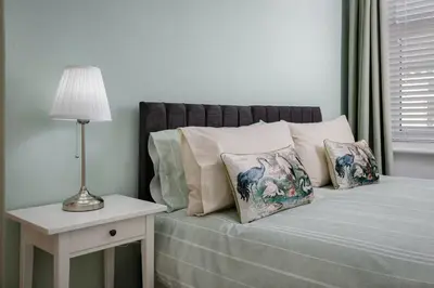 a bed with pillows and a table with a lamp at Comfy 3-Bed, Sleeps 5 & Parking in Blackpool