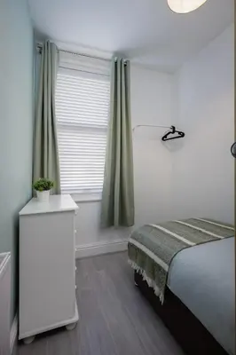 a white bedroom with a bed and a window at Comfy 3-Bed, Sleeps 5 & Parking in Blackpool