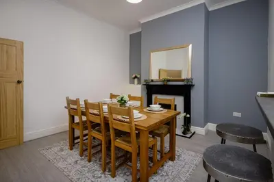 a dining room with a table and chairs and a mirror at Comfy 3-Bed, Sleeps 5 & Parking in Blackpool
