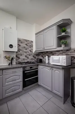 a kitchen with white cabinets and white appliances at Comfy 3-Bed, Sleeps 5 & Parking in Blackpool