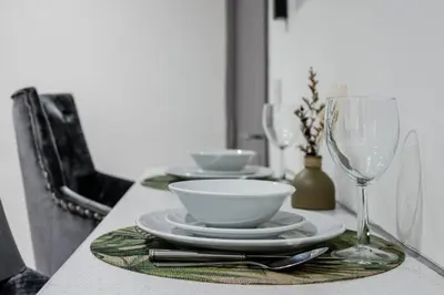 a table with plates and bowls and a wine glass at Sutcliffe House - Air Host & Stay - 3 bed 3 bath - Contractor Friendly in Liverpool