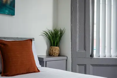 a bed with a pillow and a plant next to a door at Sutcliffe House - Air Host & Stay - 3 bed 3 bath - Contractor Friendly in Liverpool
