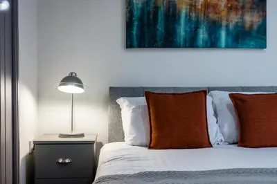 a bed with orange pillows and a lamp on a table at Sutcliffe House - Air Host & Stay - 3 bed 3 bath - Contractor Friendly in Liverpool