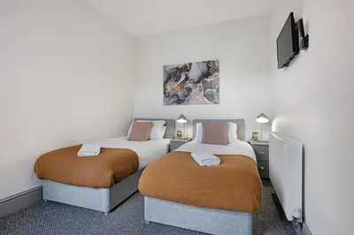 two beds in a room with a tv on the wall at Sutcliffe House - Air Host & Stay - 3 bed 3 bath - Contractor Friendly in Liverpool
