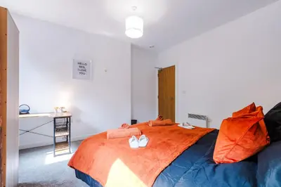 a bedroom with a large bed with orange sheets at Pool Table, Stunning 2Bed Apt, Central Location in Liverpool