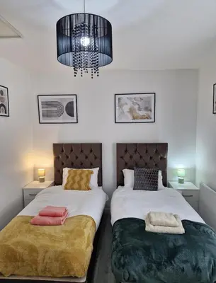 a bedroom with two beds and a chandelier at Ampee Guest Suite-Free Parking in Liverpool