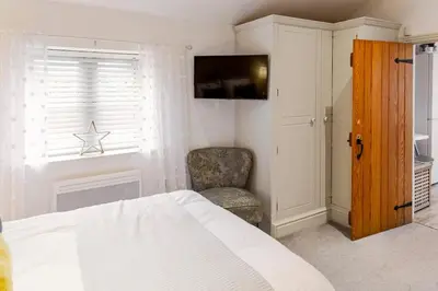 a bedroom with a bed and a chair and a television at The Lodge at Greenbank Farm