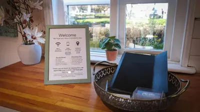 a welcome sign and a basket on a table with a window at 1 Top Locks Cottage in Burscough