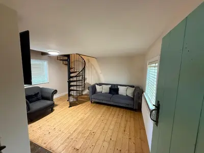 a living room with two couches and a spiral staircase at 1 Top Locks Cottage in Burscough