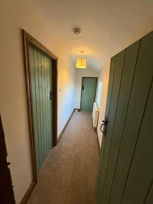 an empty hallway with green doors and carpet at 1 Top Locks Cottage in Burscough