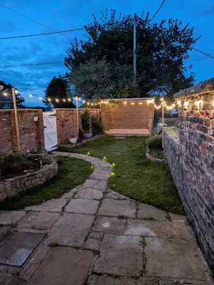 a garden at night with a fence and lights at 1 Top Locks Cottage in Burscough