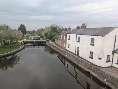 a river in a city with a building and a canal at 1 Top Locks Cottage in Burscough