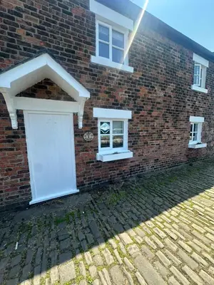 a brick building with a white door and windows at 1 Top Locks Cottage in Burscough