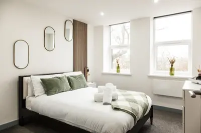 a bedroom with a bed and two windows at Comfortable Apartment In The Centre Of Preston in Preston