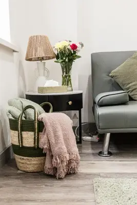 a living room with a chair and a table with a vase of flowers at Comfortable Apartment In The Centre Of Preston in Preston
