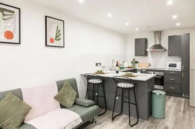 a living room with a couch and a kitchen at Comfortable Apartment In The Centre Of Preston in Preston