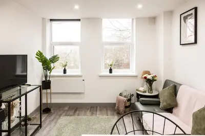 a living room with a couch and two windows at Comfortable Apartment In The Centre Of Preston in Preston