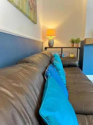 a brown leather couch with blue pillows on it at Your ideal 3-bedroom home to stay in Leyland in Leyland