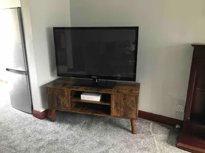 a flat screen tv sitting on top of a wooden entertainment center at Preston 4 bedroom house near M55 & M6 in Woodplumpton