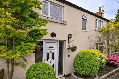 a white house with a white door and some bushes at Beautiful apartment at field view cottage in Eccleston