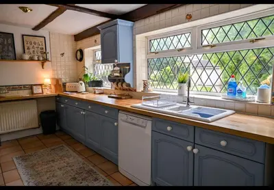 a kitchen with blue cabinets and a sink and a window at Beautiful apartment at field view cottage in Eccleston