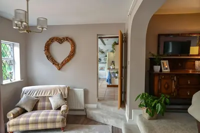 a living room with a heart shaped mirror on the wall at Beautiful apartment at field view cottage in Eccleston