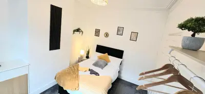 a white bedroom with a bed and a chair at Comfortable 3BR - Sleeps 5 - Fast WiFi -Parking in Barrow in Furness