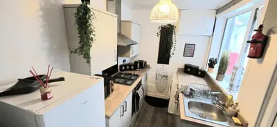 a kitchen with white cabinets and a sink and a stove at Comfortable 3BR - Sleeps 5 - Fast WiFi -Parking in Barrow in Furness