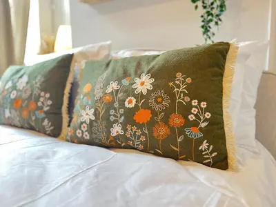 a pillow with flowers on it sitting on a bed at #55 Spacious2BR End-Terrace in Kensington Sleeps 6 in Liverpool