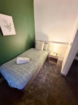 a small bedroom with a bed with a green wall at #49 Luxury 4-Bedroom House with Modern Comforts in Liverpool