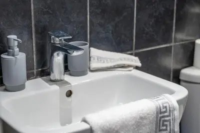 a bathroom with a sink with a faucet and towels at #49 Luxury 4-Bedroom House with Modern Comforts in Liverpool