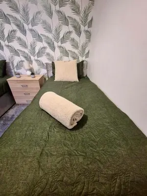 a bed with a green blanket and a pillow on it at #49 Luxury 4-Bedroom House with Modern Comforts in Liverpool