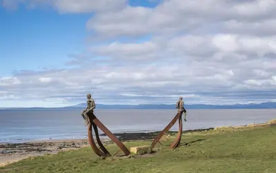 two people standing on top of a sculpture by the beach at Historic 1629 May Cottage with Hot Tub in Heysham