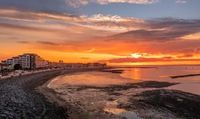 a beach with a sunset in the background at Historic 1629 May Cottage with Hot Tub in Heysham