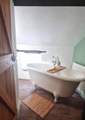 a bath tub in a bathroom with a sink at Historic 1629 May Cottage with Hot Tub in Heysham