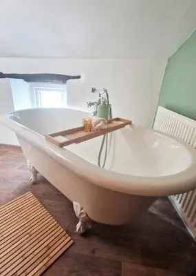 a bath tub with a faucet in a bathroom at Historic 1629 May Cottage with Hot Tub in Heysham
