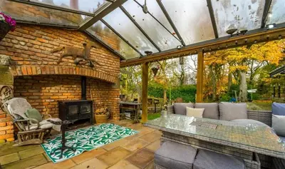 an outdoor living room with a fireplace and a brick wall at Fitzys Apartment Wellness Retreat