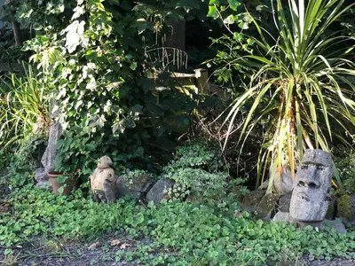 a garden with some stone statues in the grass at Fitzys Coach House - Wellness Retreat