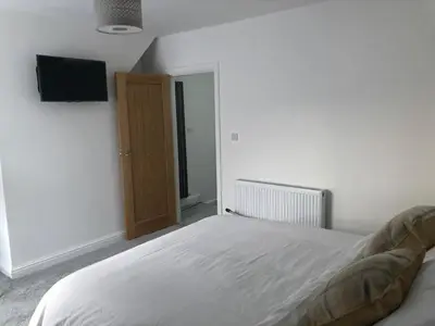 a bedroom with a bed and a flat screen tv at Fitzys Terrace Three Bed in Accrington
