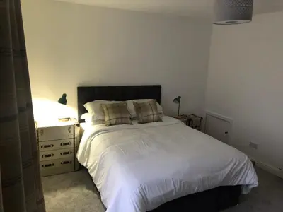 a bedroom with a white bed and a dresser at Fitzys Terrace Three Bed in Accrington