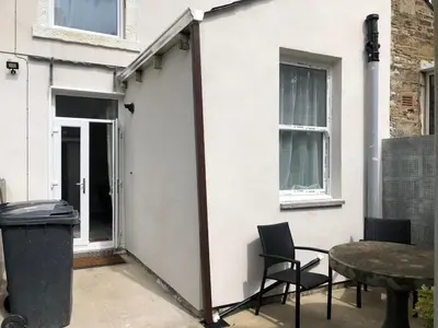 a patio with chairs and a table in front of a house at Fitzys Terrace Three Bed in Accrington
