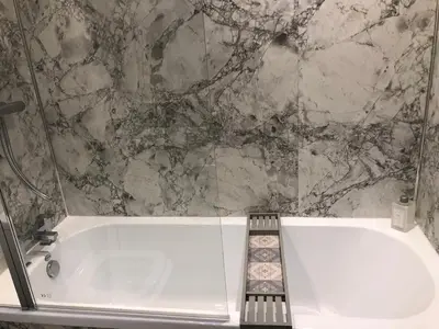 a white bath tub in a bathroom with a marble wall at Fitzys Terrace Three Bed in Accrington