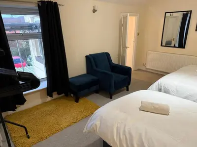 a bedroom with a bed and a chair and a window at Oswaldtwistle Spacious 3 Bedroom Two Bath in Oswaldtwistle