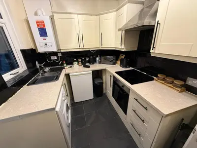 a small kitchen with white cabinets and a sink at Oswaldtwistle Spacious 3 Bedroom Two Bath in Oswaldtwistle